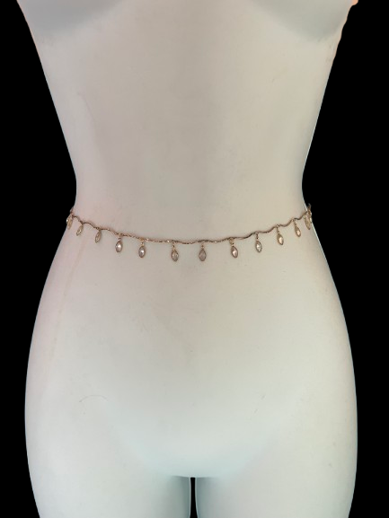 A delicate rose gold chain belly chain with small dangling teardrop charms, displayed on a white mannequin torso against a solid black background.