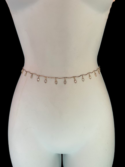 A delicate rose gold chain belly chain with small dangling teardrop charms, displayed on a white mannequin torso against a solid black background.
